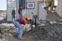 Workers at a remote site in Maine lay discharge pipe from a Lifewater Engineering system. The wood framing around the door enables the attachment of a 4- by 8-foot-long arctic entry. The framing around the windows enables the staff to screw on plywood sheets if flying ice or debris breaks the glass.