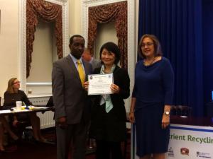 Hiroko Yoshida (center), senior R&D engineer and project leader of Centrisys, receives the EPA Nutrient Recycling Challenge award on behalf of the Centrisys team at the White House Eisenhower Executive Office Building in the District of Columbia