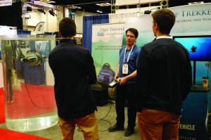 Sean Phillips, center, engineering manager for Deep Trekker, demonstrates a DTG2 ROV camera inspection system for two interested WWETT Show attendees. The unit allows users to inspect tank walls and underwater components without having to enter or drain the tank. (Photo by Craig Mandli)